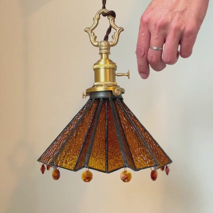     Amber stained glass pendant light glowing warmly in a cozy vintage interior