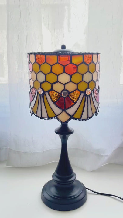 Stained glass may look different when the lamp is turned on and off. In natural daylight, the glass shows more individual color variation and texture. When lit, the amber and cream tones become warmer and softer.